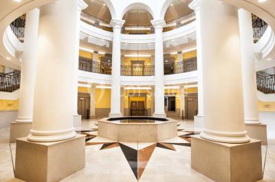 Salle spacieuse avec parquet en bois clair, colonnes blanches, plafonds ondulés et luminaires suspendus.