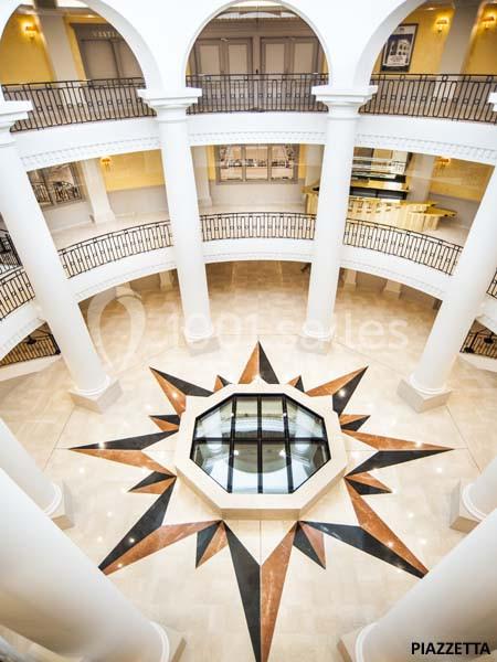 Vue intérieure d'un bâtiment avec une verrière centrale en forme d'étoile et des balustrades entourant les étages supérieurs.
