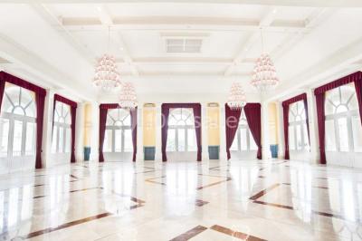 Salle de conférence lumineuse avec des rangées de chaises blanches et une table en bois au premier plan.