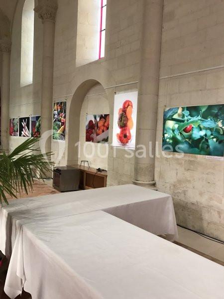Exposition de photographies de fruits et légumes accrochées sur un mur en pierre dans un espace lumineux.
