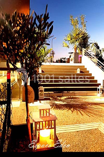Escalier extérieur éclairé par des lanternes, entouré de végétation et d'arbres sous un ciel nocturne clair.
