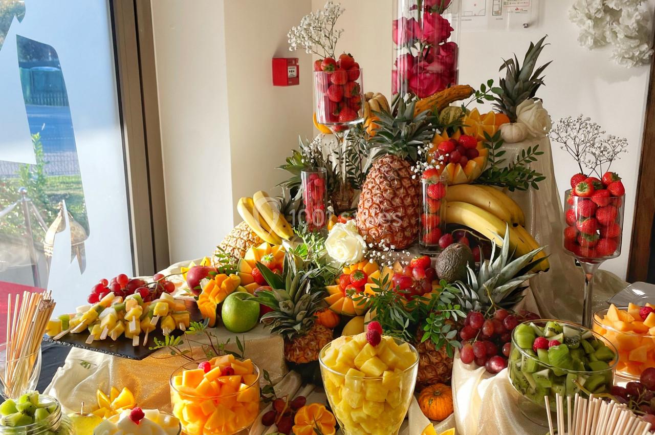 Buffet coloré de fruits frais variés, disposés sur une table décorée avec des fleurs et des éléments élégants.