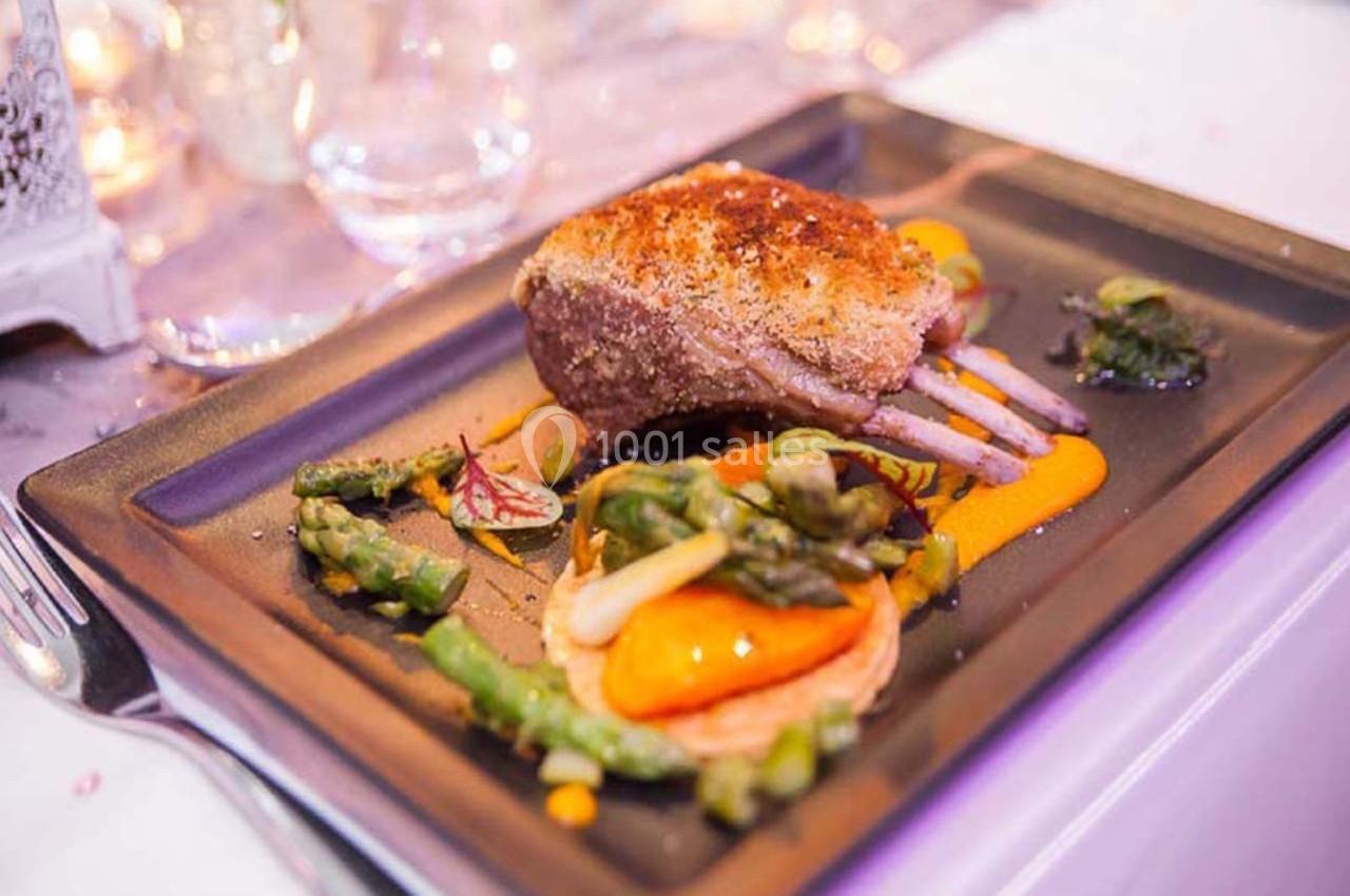 Carré d'agneau rôti avec purée de carottes, asperges et tartelette de légumes, servi sur une assiette élégante.