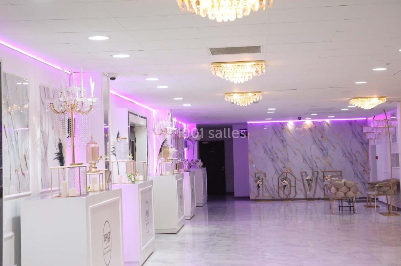 Salle lumineuse avec décoration élégante, murs en marbre, lustres en cristal et éclairage LED violet.