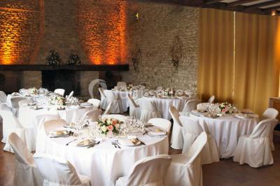Salle de réception en pierre décorée de ballons rouges et blancs, avec tables dressées pour un événement.
