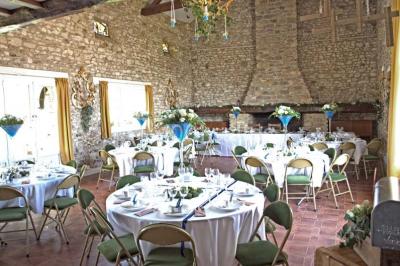 Salle de réception en pierre décorée de ballons rouges et blancs, avec tables dressées pour un événement.