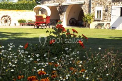 Salle de réception en pierre décorée de ballons rouges et blancs, avec tables dressées pour un événement.