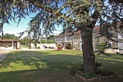 Salle de réception en pierre décorée de ballons rouges et blancs, avec tables dressées pour un événement.