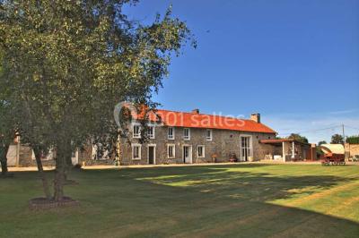 Salle de réception en pierre décorée de ballons rouges et blancs, avec tables dressées pour un événement.