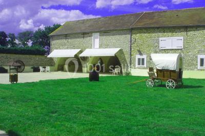 Salle de réception en pierre décorée de ballons rouges et blancs, avec tables dressées pour un événement.