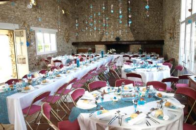 Salle de réception en pierre décorée de ballons rouges et blancs, avec tables dressées pour un événement.