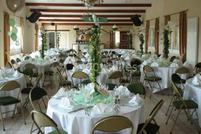 Salle de réception en pierre décorée de ballons rouges et blancs, avec tables dressées pour un événement.