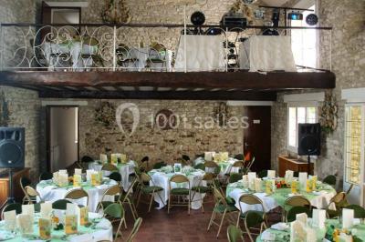 Salle de réception en pierre décorée de ballons rouges et blancs, avec tables dressées pour un événement.