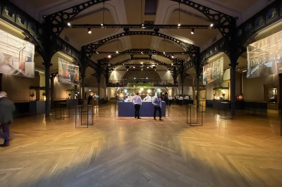 Salle intérieure avec mezzanine, escaliers symétriques, balustrades en métal décoratif et parquet au sol.