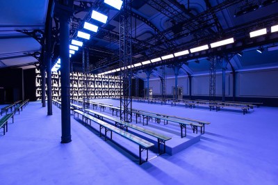 Salle intérieure avec mezzanine, escaliers symétriques, balustrades en métal décoratif et parquet au sol.