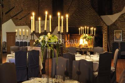 Miniature Location salle Pont-à-Celles (Hainaut) - La Ferme de la Pitance #5 Salle de réception avec tables dressées, nappes beiges, chandeliers et poutres apparentes sous un toit vitré.