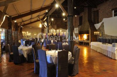 Miniature Location salle Pont-à-Celles (Hainaut) - La Ferme de la Pitance #7 Table et chaises en métal sur une terrasse en dalles, devant un mur blanc avec une porte en bois et des plantes décoratives.