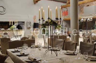 Miniature Location salle Pont-à-Celles (Hainaut) - La Ferme de la Pitance #11 Table et chaises en métal sur une terrasse en dalles, devant un mur blanc avec une porte en bois et des plantes décoratives.