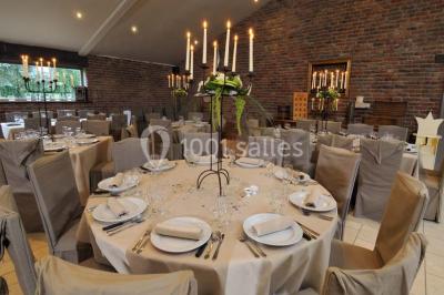 Miniature Location salle Pont-à-Celles (Hainaut) - La Ferme de la Pitance #9 Table et chaises en métal sur une terrasse en dalles, devant un mur blanc avec une porte en bois et des plantes décoratives.