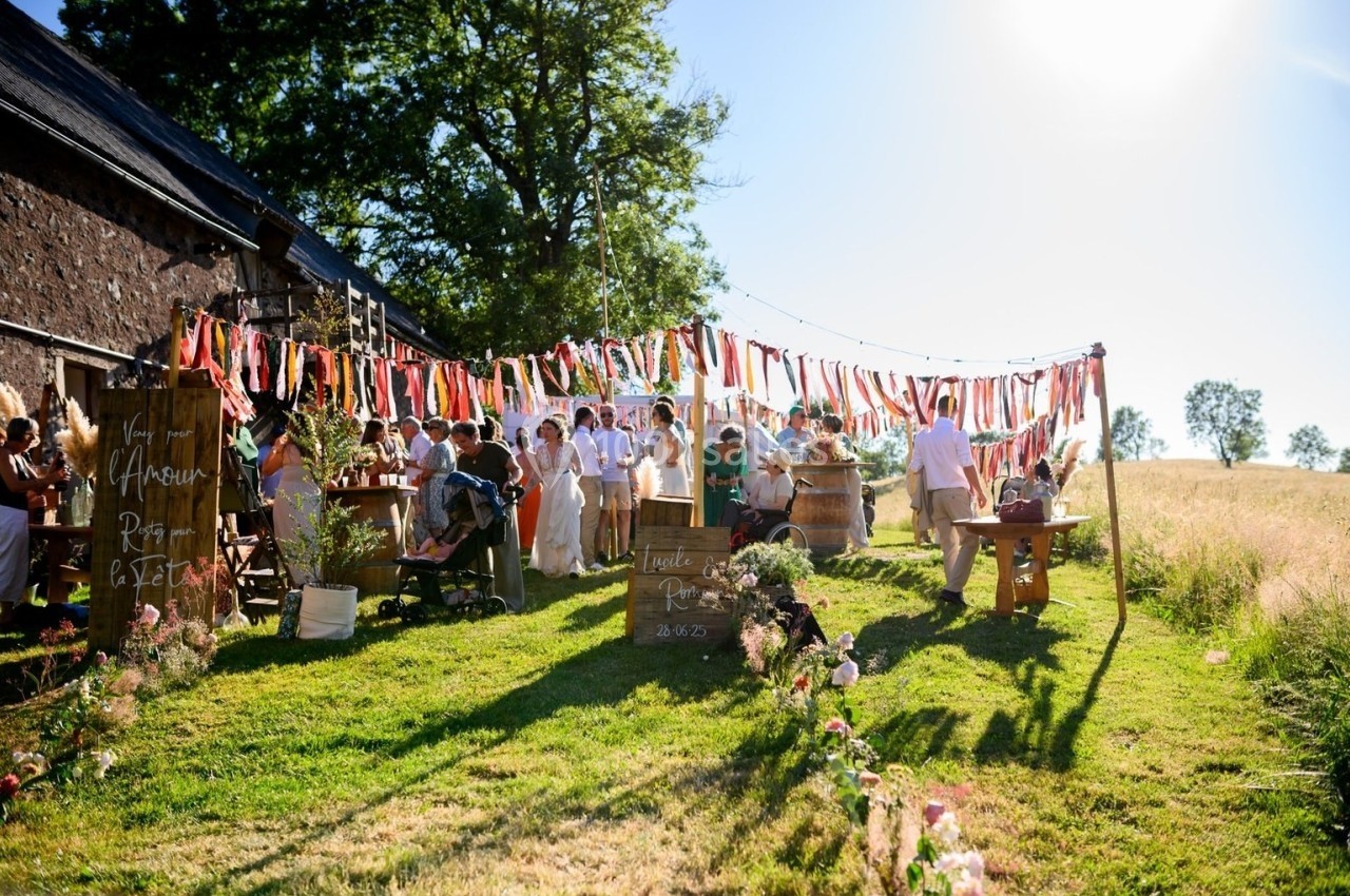 Groupe de personnes réunies dans un jardin décoré de guirlandes colorées, lors d'une fête en plein air.
