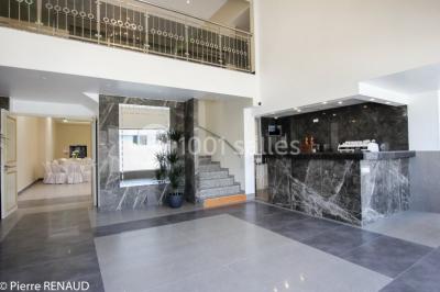 Salle de réception décorée avec une table dressée, un centre de table floral et une arche fleurie en arrière-plan.