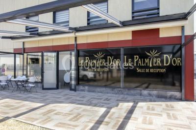 Salle de réception décorée avec une table dressée, un centre de table floral et une arche fleurie en arrière-plan.
