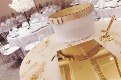 Salle de réception décorée avec une table dressée, un centre de table floral et une arche fleurie en arrière-plan.