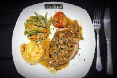 Salle de réception décorée avec une table dressée, un centre de table floral et une arche fleurie en arrière-plan.