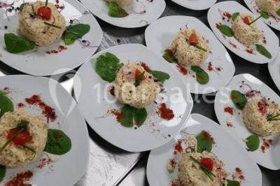 Salle de réception décorée avec une table dressée, un centre de table floral et une arche fleurie en arrière-plan.