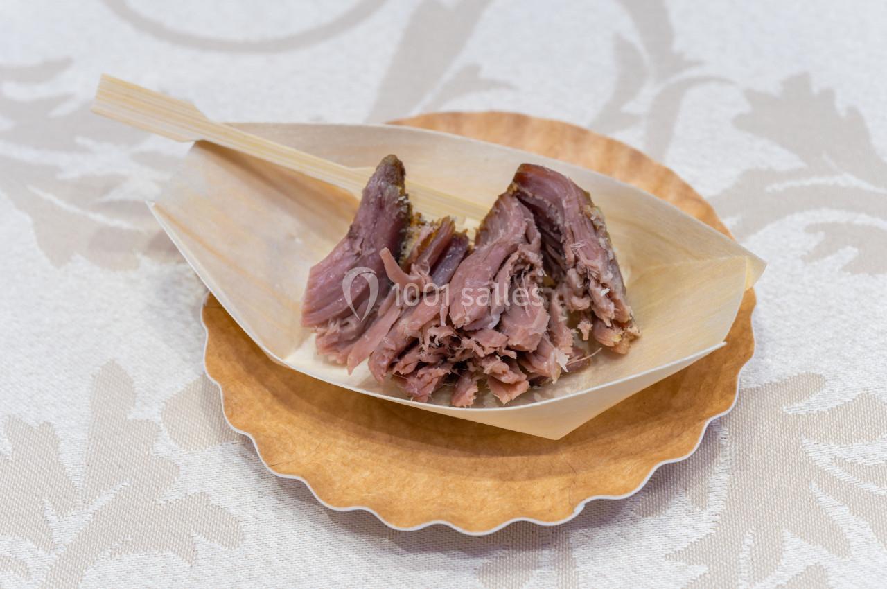 Morceaux de viande effilochée servis dans un plat en bois sur une assiette, avec un fond de nappe claire.