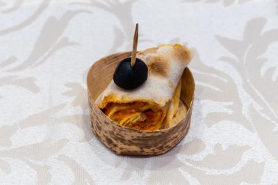 Salle de réception décorée avec une table dressée, un centre de table floral et une arche fleurie en arrière-plan.