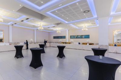 Salle de réception décorée avec une table dressée, un centre de table floral et une arche fleurie en arrière-plan.