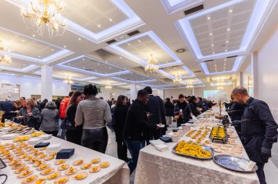 Salle de réception décorée avec une table dressée, un centre de table floral et une arche fleurie en arrière-plan.