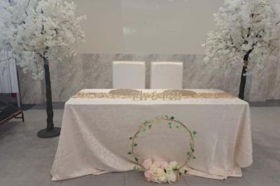 Salle de réception décorée avec une table dressée, un centre de table floral et une arche fleurie en arrière-plan.