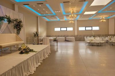 Salle de réception décorée avec une table dressée, un centre de table floral et une arche fleurie en arrière-plan.