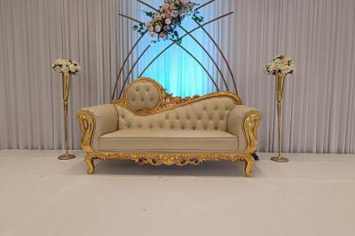 Salle de réception décorée avec une table dressée, un centre de table floral et une arche fleurie en arrière-plan.