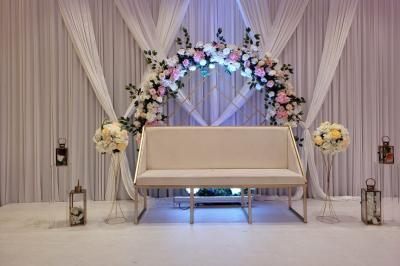 Salle de réception décorée avec une table dressée, un centre de table floral et une arche fleurie en arrière-plan.