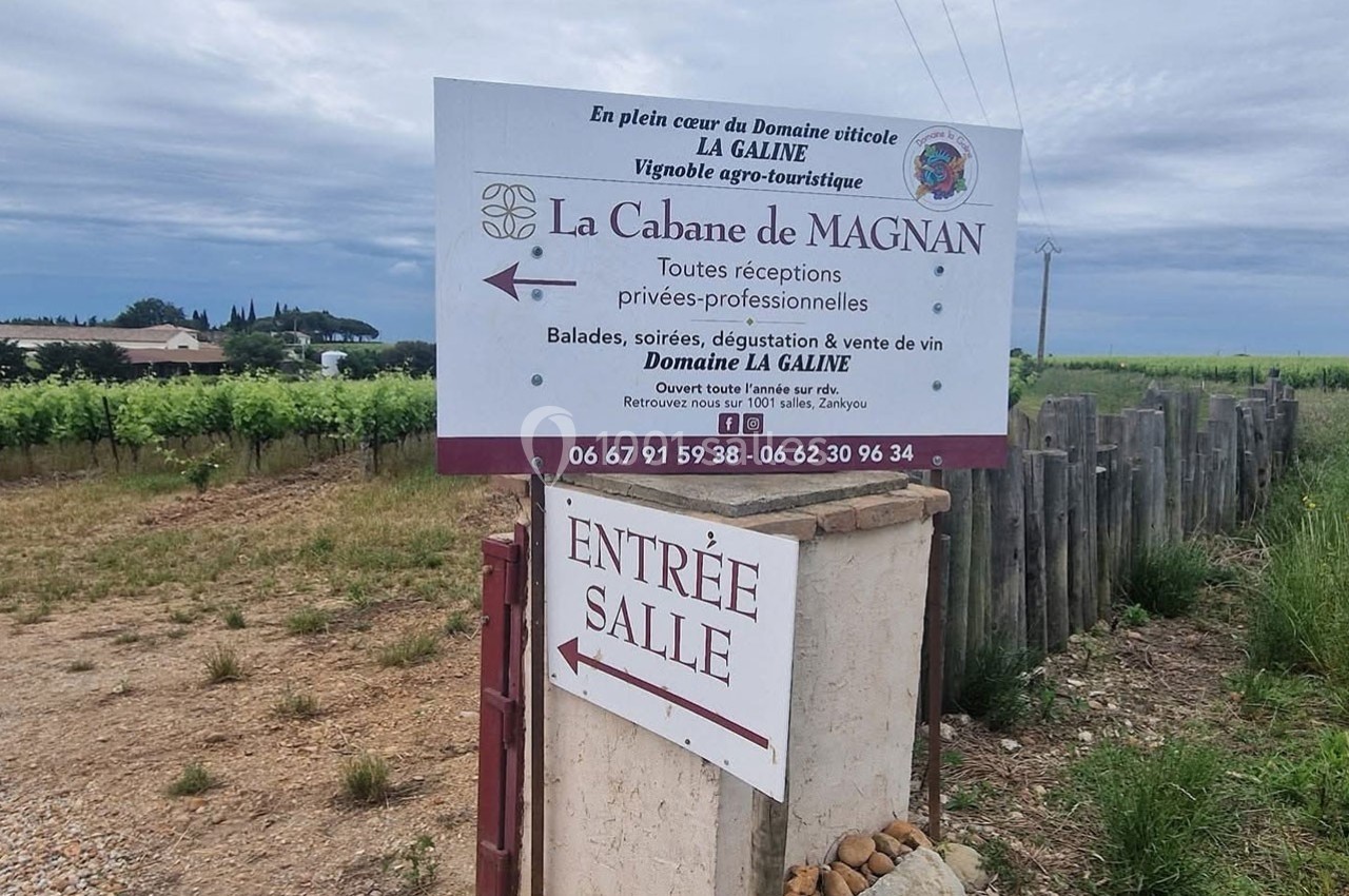 Panneau indiquant l'entrée de ’La Cabane de Magnan’ dans un domaine viticole, avec vignes en arrière-plan.
