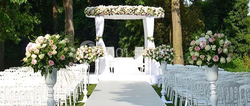 Location salle Rueil-Malmaison (Hauts-de-Seine) - Paris Country Club #19 Allée centrale décorée de fleurs blanches et roses menant à une arche de mariage dans un jardin verdoyant.