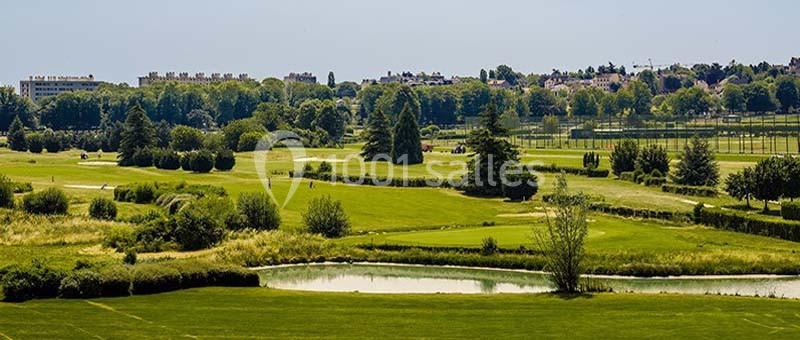 Location salle Rueil-Malmaison (Hauts-de-Seine) - Paris Country Club #20 Vue d'un vaste terrain de golf verdoyant avec des arbres, un étang et des bâtiments en arrière-plan.