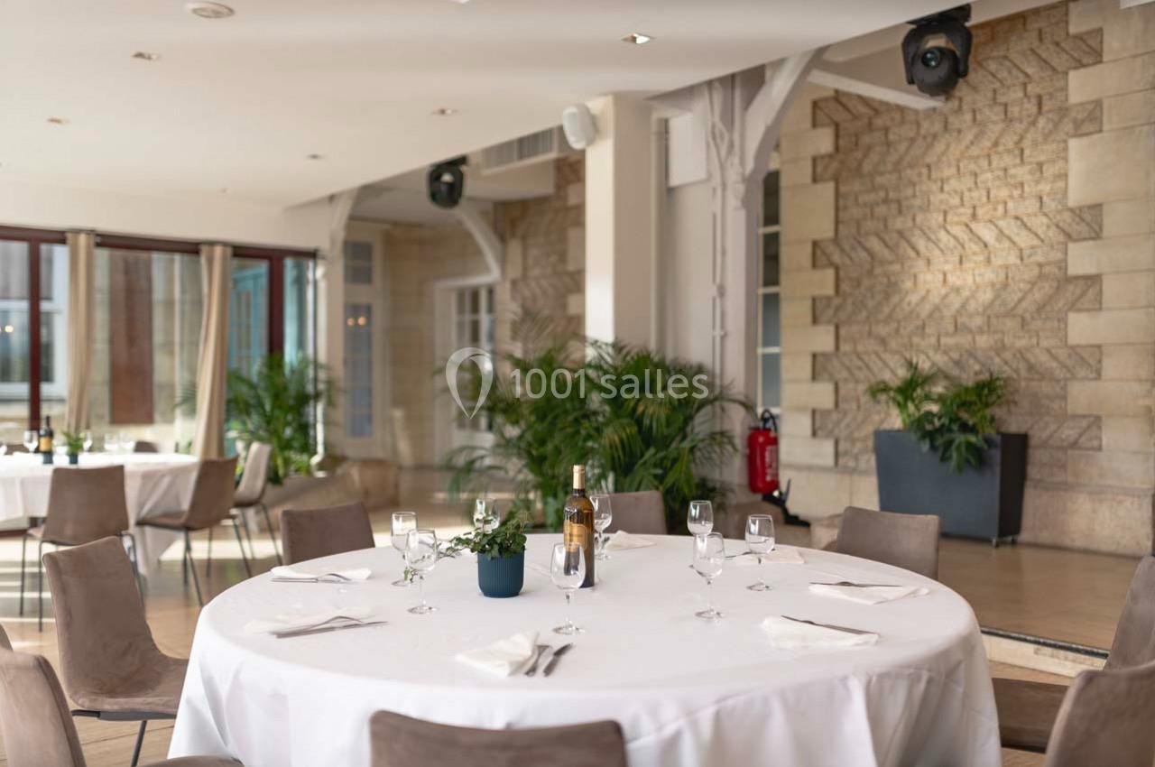 Location salle Rueil-Malmaison (Hauts-de-Seine) - Paris Country Club #17 Salle lumineuse avec tables rondes dressées, nappes blanches, chaises beige et plantes en décoration.