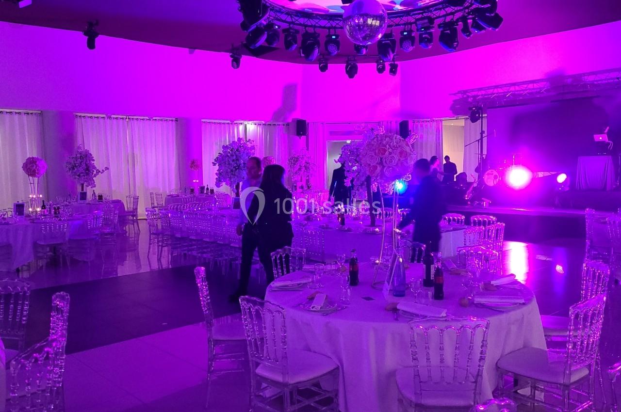 Location salle Rueil-Malmaison (Hauts-de-Seine) - Paris Country Club #24 Salle de réception décorée avec des tables rondes, des chaises transparentes et un éclairage violet tamisé.