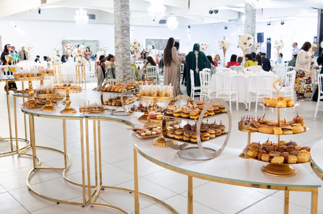 Buffet de desserts variés disposés sur des présentoirs dorés dans une salle de réception élégante.
