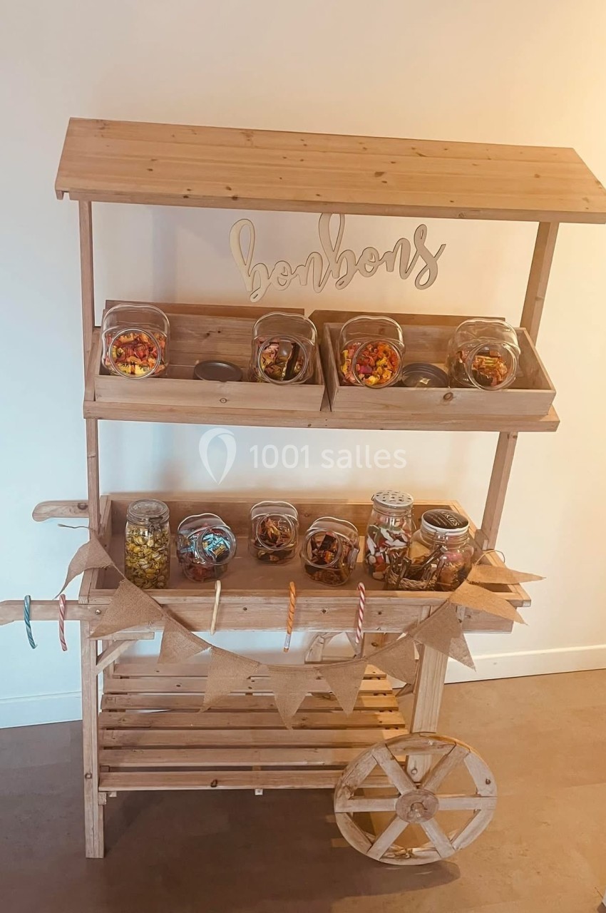 Chariot en bois avec des bocaux remplis de bonbons colorés, décoré de guirlandes et d'une inscription ’bonbons’.