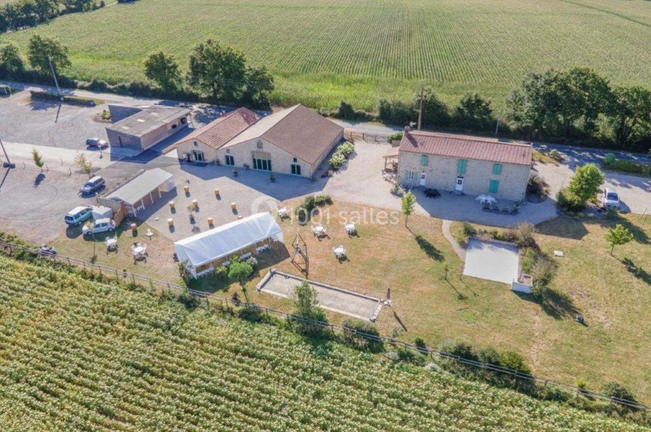 Vue aérienne d'un domaine rural avec bâtiments, serre, espace aménagé et champs environnants.