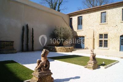 Allée éclairée par des lampes au sol, bordée d'arbres et menant à une entrée illuminée dans l'obscurité.