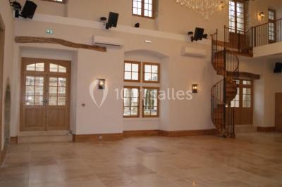 Allée éclairée par des lampes au sol, bordée d'arbres et menant à une entrée illuminée dans l'obscurité.