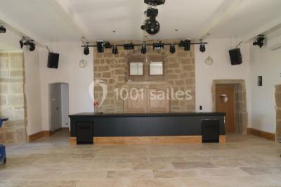 Allée éclairée par des lampes au sol, bordée d'arbres et menant à une entrée illuminée dans l'obscurité.