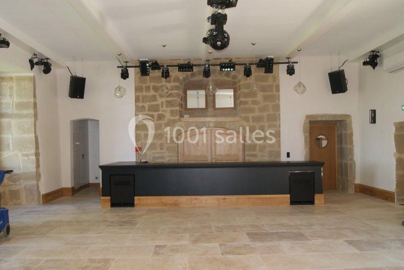 Salle intérieure en pierre avec un comptoir en bois, éclairages suspendus et sol en carrelage beige.