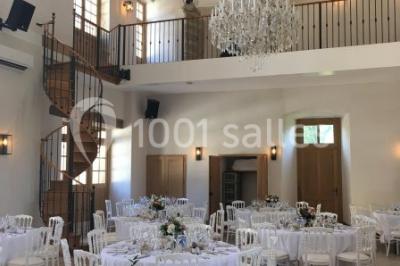 Allée éclairée par des lampes au sol, bordée d'arbres et menant à une entrée illuminée dans l'obscurité.